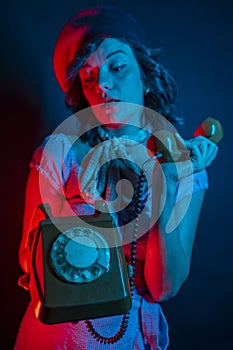 Young Woman Talking on Orange Retro Phone. High Fashion model woman in colorful bright neon blue and purple lights posing in