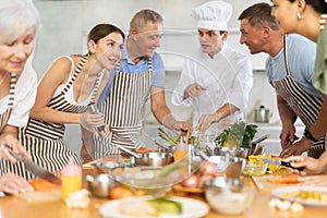 Young woman talking with participants at group culinary class