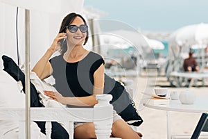 A young woman is talking on the phone on the beach