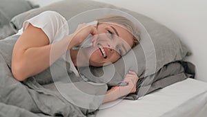 Young Woman Talking on phone while Lying on Side in Bed