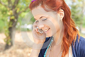 Young woman talking on phone and smiling outdoors