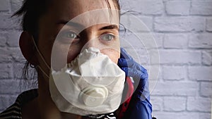 Young woman talking on the phone in a white mask. Coronavirus protection. epidemic precautions. A brunette in a medical mask holds
