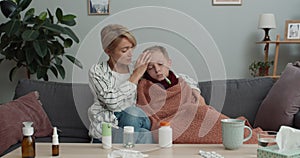 Young woman talking while sitting on sofa with ill son and looking to camera. Mother and her boy kid having video