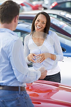 Young woman talking to car salesman
