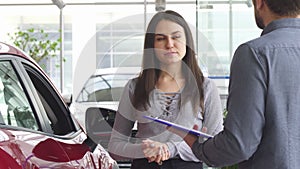 Young woman talking to the salesman at the car dealership