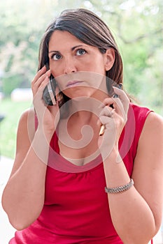 Young woman talks on phone while holding pen