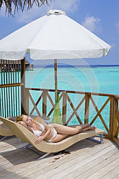 Young woman tans on villa on ocean Maldives