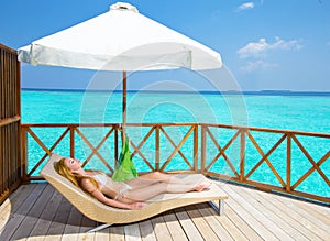 Young woman tans on villa on ocean Maldives
