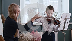 Young woman teacher teaching a little girl how to properly hold a bow while playing violin