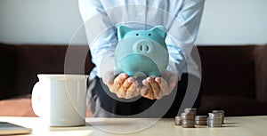 A young woman teaches how to put coins in a piggy bank start a growing business for success and save for retirement concept