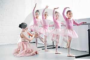 young woman teaching adorable children dancing in ballet