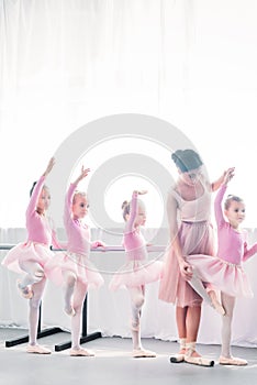 young woman teaching adorable kids dancing in ballet