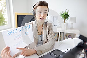 Young woman is teaching english with laptop computer, camcorder and headphone online at home. Teacher is having video conference