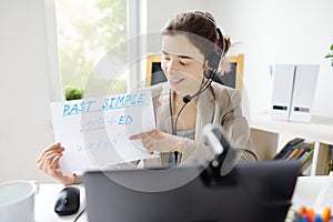 Young woman is teaching english with laptop computer, camcorder and headphone online at home. Teacher is having video conference