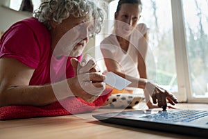 Young woman teaching a senior man how to use a laptop computer for online shopping and education