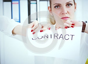 Angry woman tears agreement documents in front of camera closeup.