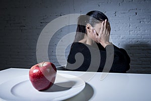 Young woman or teen with apple fruit on dish as symbol of crazy diet in nutrition disorder