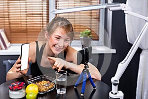 Young woman, teen girl holding cell phone, touching forefinger mock up white blank display for social media app ad at home in