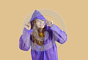 Young woman or teen girl in purple raincoat smiling and looking up from under hood