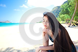 Young woman or teen sitting on Hawaiian beach, thinking