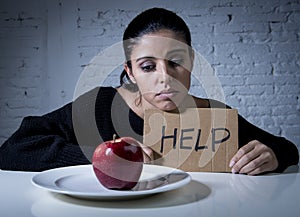 Young woman or teen looking apple fruit on dish as symbol of crazy diet in nutrition disorder