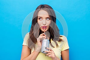 Young woman or teenage girl drinking soda from can