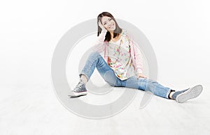 Young woman teenager in jeans sitting on white floor