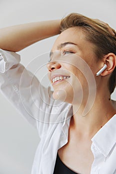Young woman teenager listening to music with infertile headphones and dancing home, grinning with teeth with a short