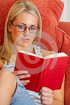 Young Woman Teenager Wearing Glasses Sitting Reading a Book at Home