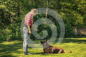 Young woman tell dog to lay down on grass,obedience training