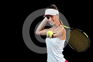 Young woman on a tennis practice. Beginner player holding a racket, learning basic skills. Portrait on black background.