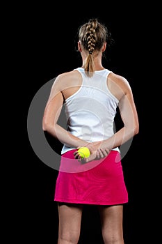 Young woman on a tennis practice. Beginner player holding a racket, learning basic skills. Portrait on black background.