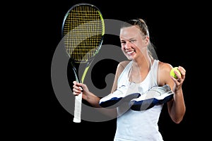 Young woman on a tennis practice. Beginner player holding a racket, learning basic skills. Portrait on black background.