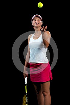 Young woman on a tennis practice. Beginner player holding a racket, learning basic skills. Portrait on black background.