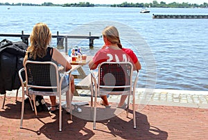 Young women outdoor terrace drinks lake view, Loosdrecht, Netherlands