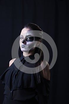 Young woman with terrifying make up posing on black background