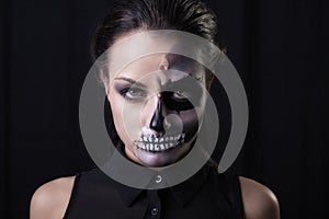 Young woman with terrifying make up posing on black background