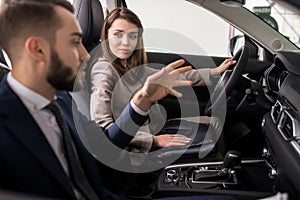 Young Woman Testing New Car in Showroom