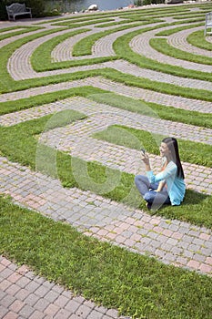 Young Woman Text Messaging in a Grass Maze