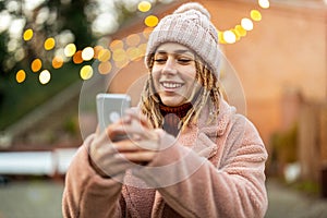 Young woman text messaging outdoors during winter