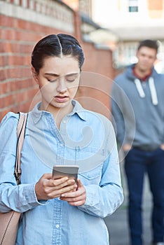 Young Woman Texting For Help On Mobile Phone Whilst Being Stalke