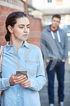 Young Woman Texting For Help On Mobile Phone Whilst Being Stalked On City Street photo