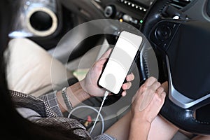 Young woman texting on her smartphone while driving a car.