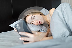 Young woman texting while lying on a bed at home