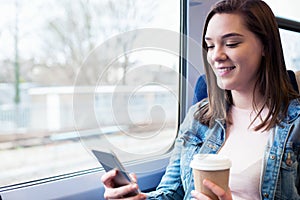 Young Woman Texting On Mobile Phone During Train Journey