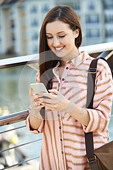 Young Woman Texting On Mobile Phone Walking To Work