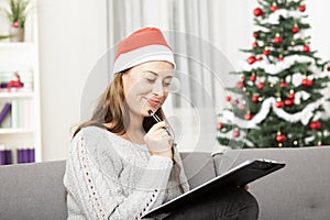Young woman think about christmas wih list