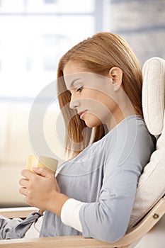 Young woman thinking, holding tea mug