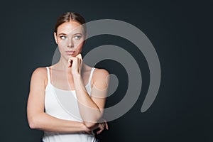 Young woman thinking and looking aside on gray banner background with copy space