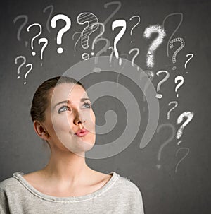 Young woman thinking with question marks over head